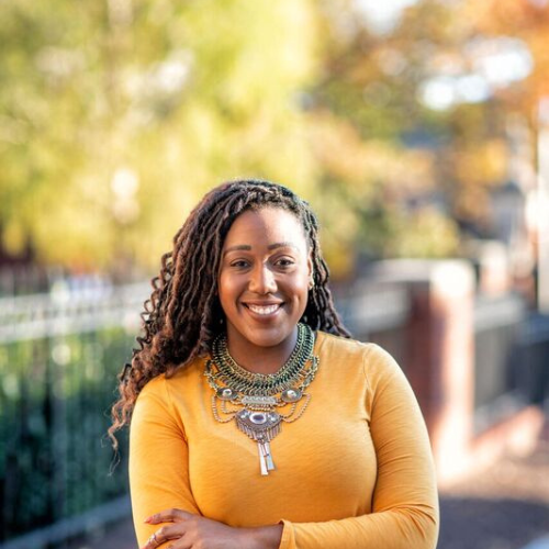 woman smiling with arms folded and a yellow shirt 