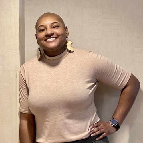 Dr. Armisha Roberts in a beige top leaning against a wall.