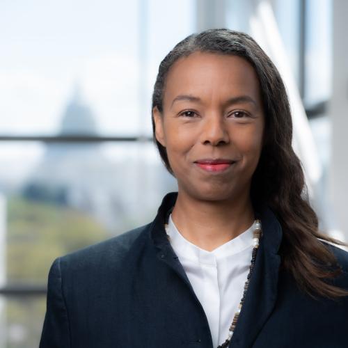 Dr. Angela R. Pashayan in front of glass wall with the U.S. Capitol in view behind her.