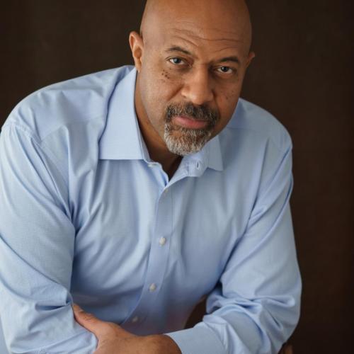 head shot of Roy Austin from waist up with arms crossed wearing a blue long sleeved button down shirt